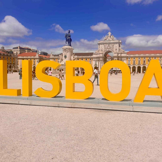 Yellow sign saying Lisboa with architecture in background