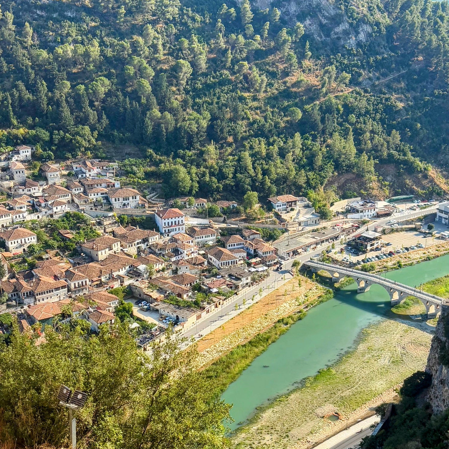 Town nestled in a valley with a river and bridge, surrounded by greenery